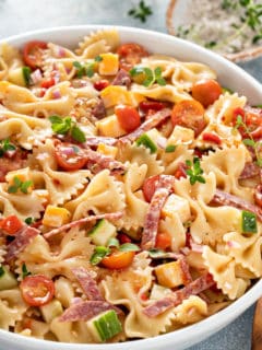 White serving bowl filled with italian pasta salad.