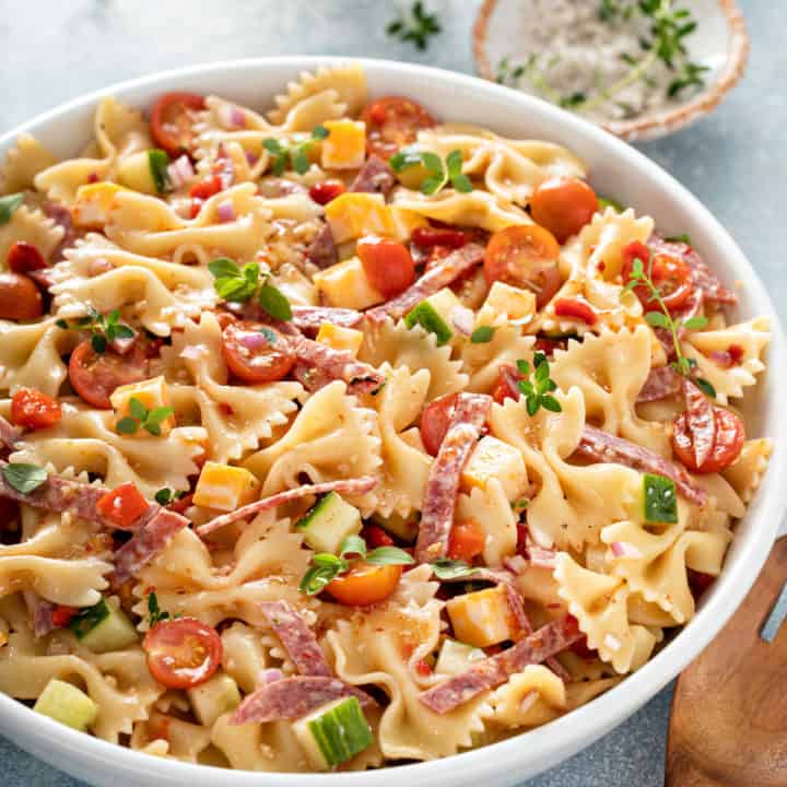White serving bowl filled with italian pasta salad.