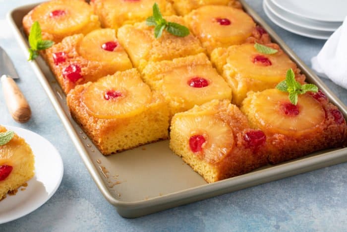 Pineapple upside down cake on a sheet pan, with the corner piece removed.