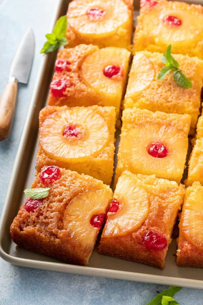 Sliced pineapple upside down cake on a sheet pan.