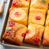 slices of pineapple upside down cake set on a sheet pan.