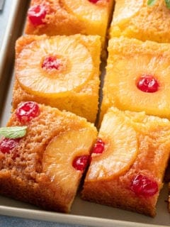 slices of pineapple upside down cake set on a sheet pan.