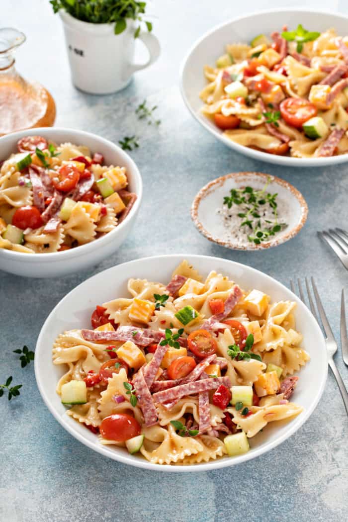 Italian pasta salad divided into three small white bowls.