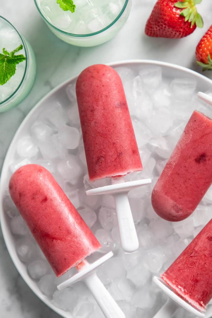 Close up of strawberry popsicles arranged on top of ice.