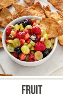 Cinnamon chip in a bowl of fruit salsa, with more cinnamon chips in the background.