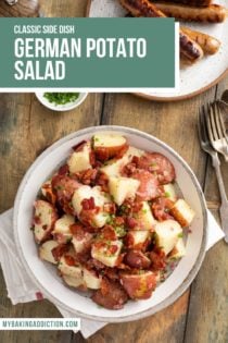 Overhead view of a serving bowl of german potato salad set on a wooden table next to a plate of grilled brats. Text overlay includes recipe name.