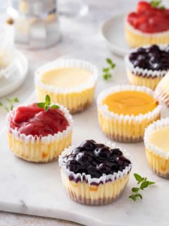 Mini cheesecakes topping with an assortment of toppings arranged on a marble slab.