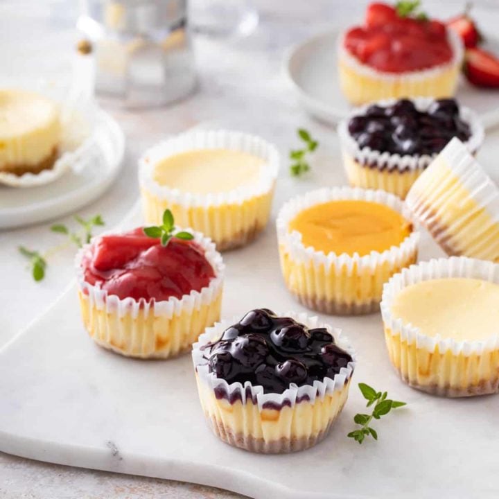 Mini cheesecakes topping with an assortment of toppings arranged on a marble slab.
