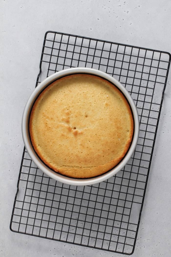 Baked yellow sponge cake on a wire cooling rack.