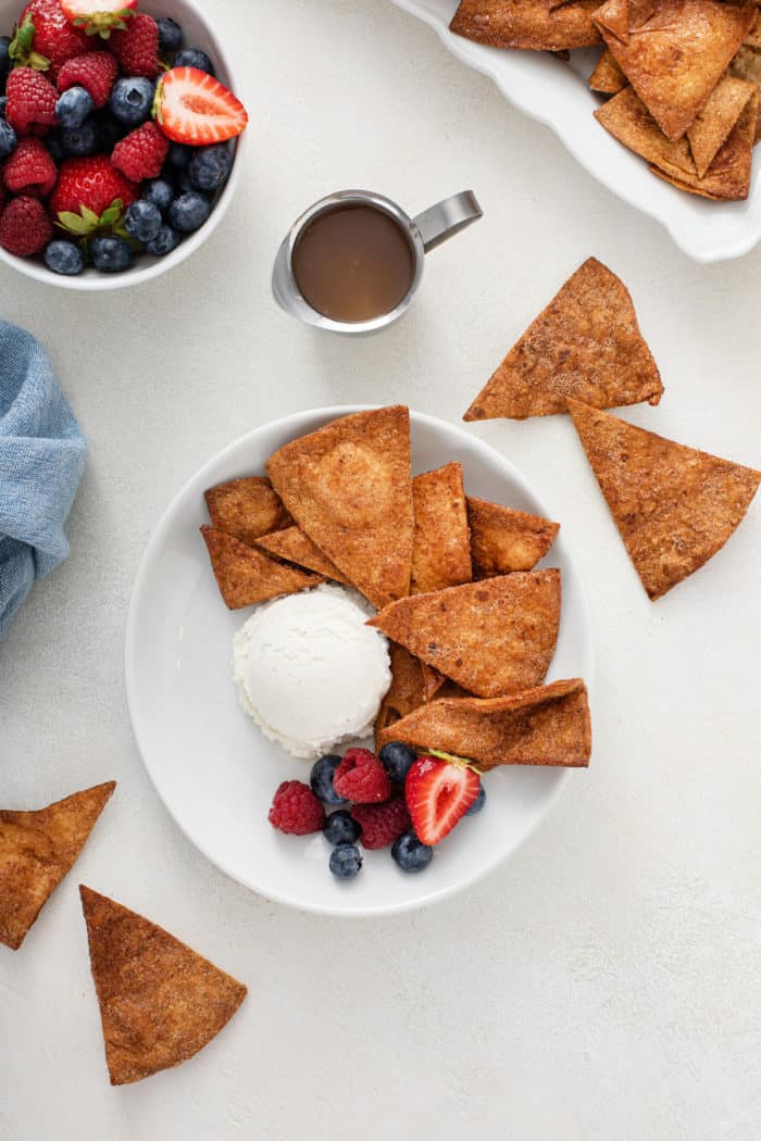 Overhead view of cinnamon tortilla chips alongside a scoop of vanilla ice cream and fresh fruit.
