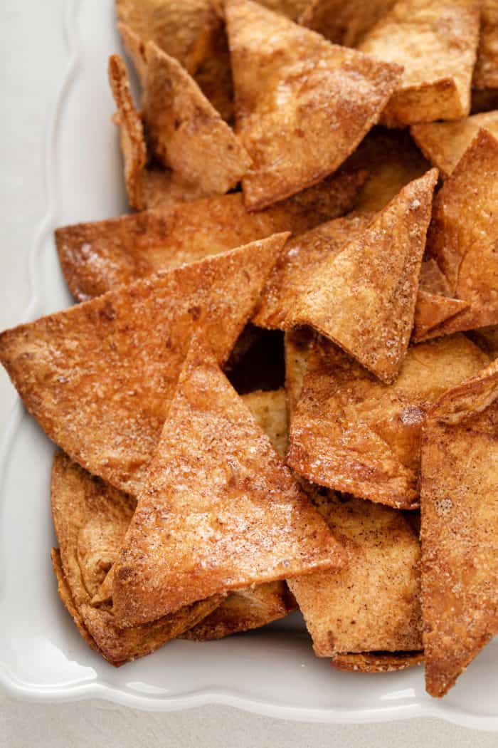 Close up of cinnamon tortilla chips arranged on a white platter.