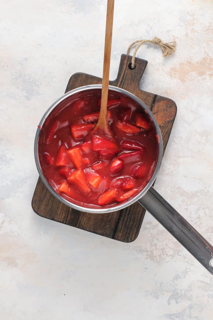 Strawberry pie filling mixed together in a metal saucepan.