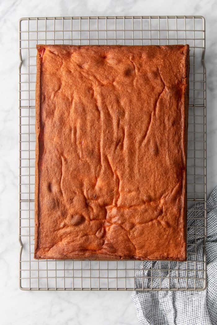 Easy strawberry cake cooling on a wire rack set on a marble countertop.