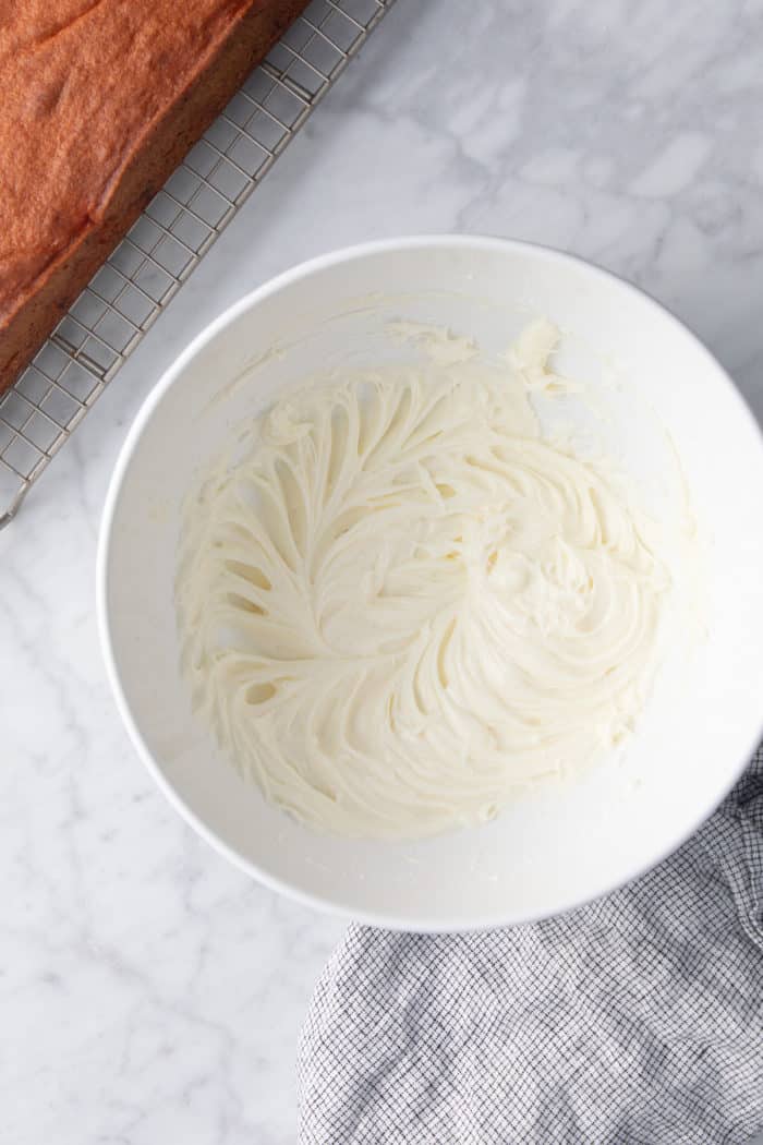 Cream cheese frosting for easy strawberry cake in a white mixing bowl.