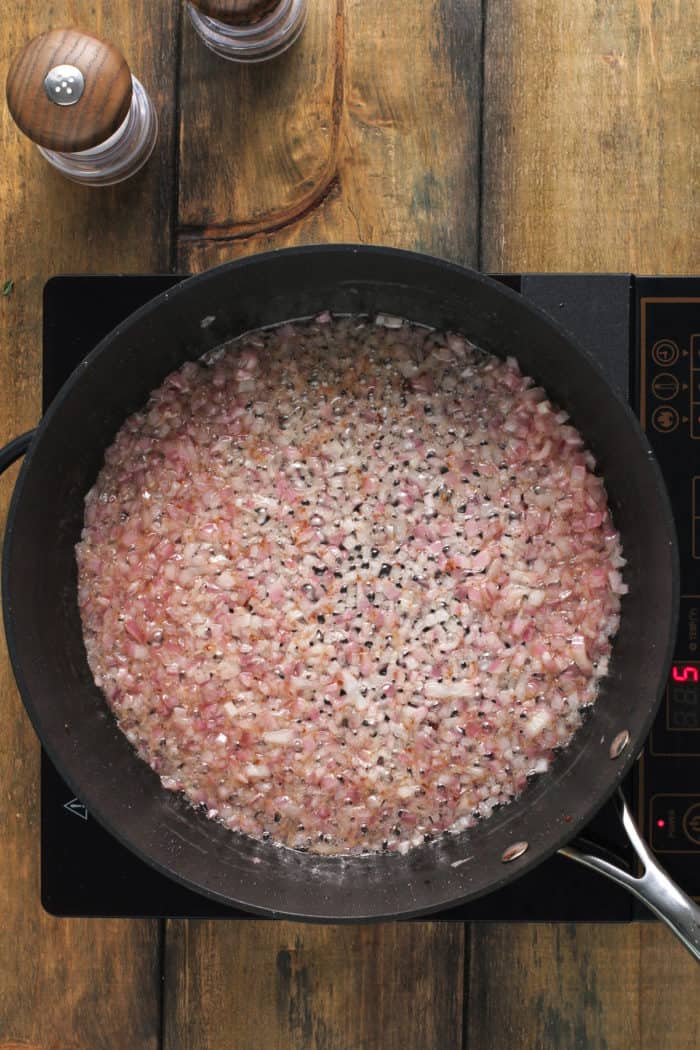 Hot bacon dressing for german potato salad being cooked in a black skillet.