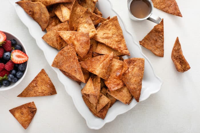 Overhead view of cinnamon tortilla chips on a white platter.