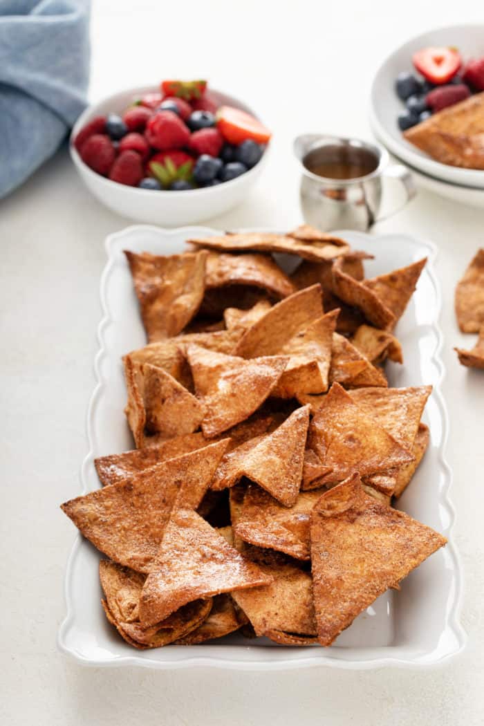 Cinnamon tortilla chips scattered on a white platter.