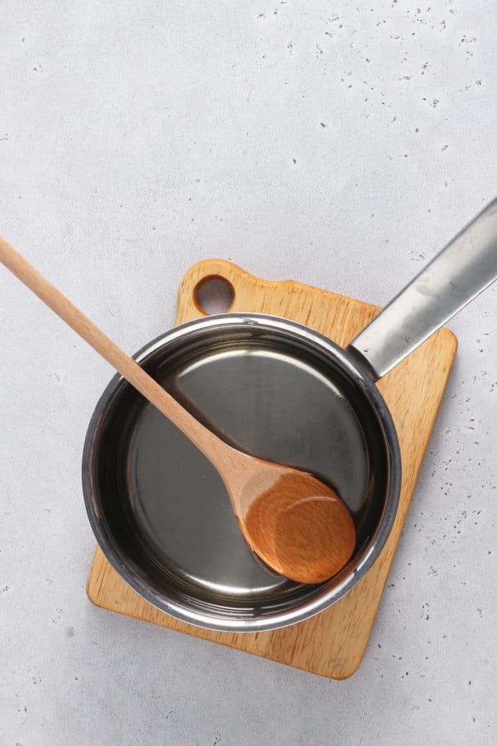 Simple syrup in a saucepot set on a wooden trivet.