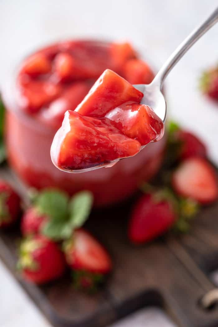 Spoon holding up a bite of strawberry pie filling.