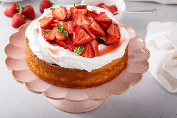Assembled strawberry shortcake on a pink cake stand.