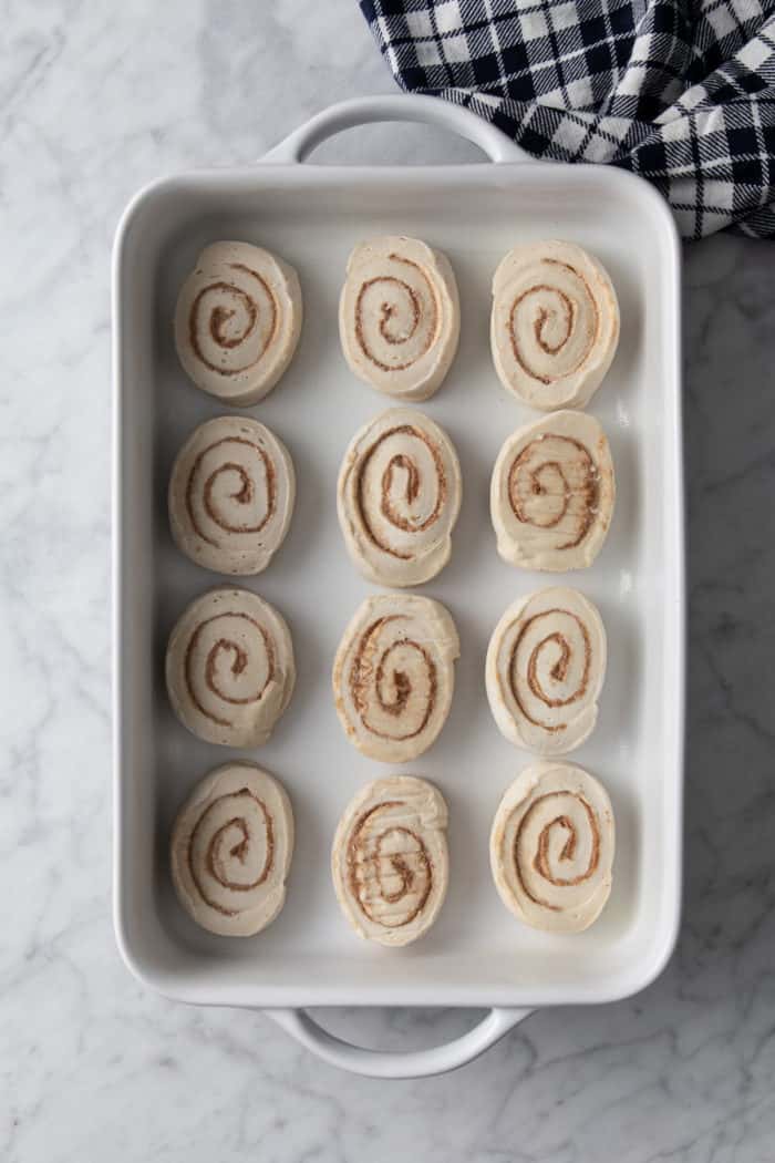 Frozen cinnamon rolls in a white baking dish, ready to thaw and rise.