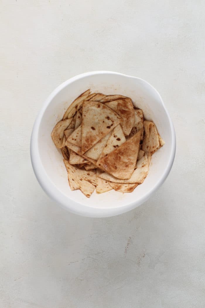 Tortilla wedges tossed with butter and cinnamon sugar in a white bowl.