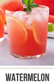 Glass of watermelon lemonade on a gray countertop. There are more glasses and a pitcher of watermelon lemonade in the background. Text overlay includes recipe name.