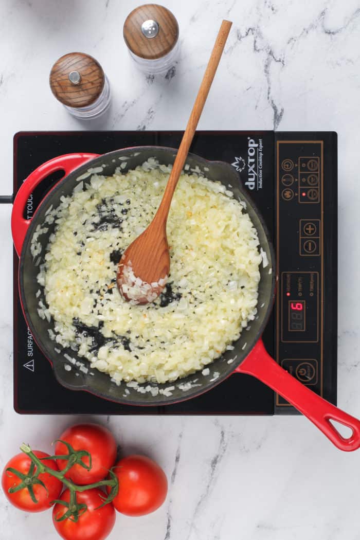 Onions being cooked in a cast iron skillet.