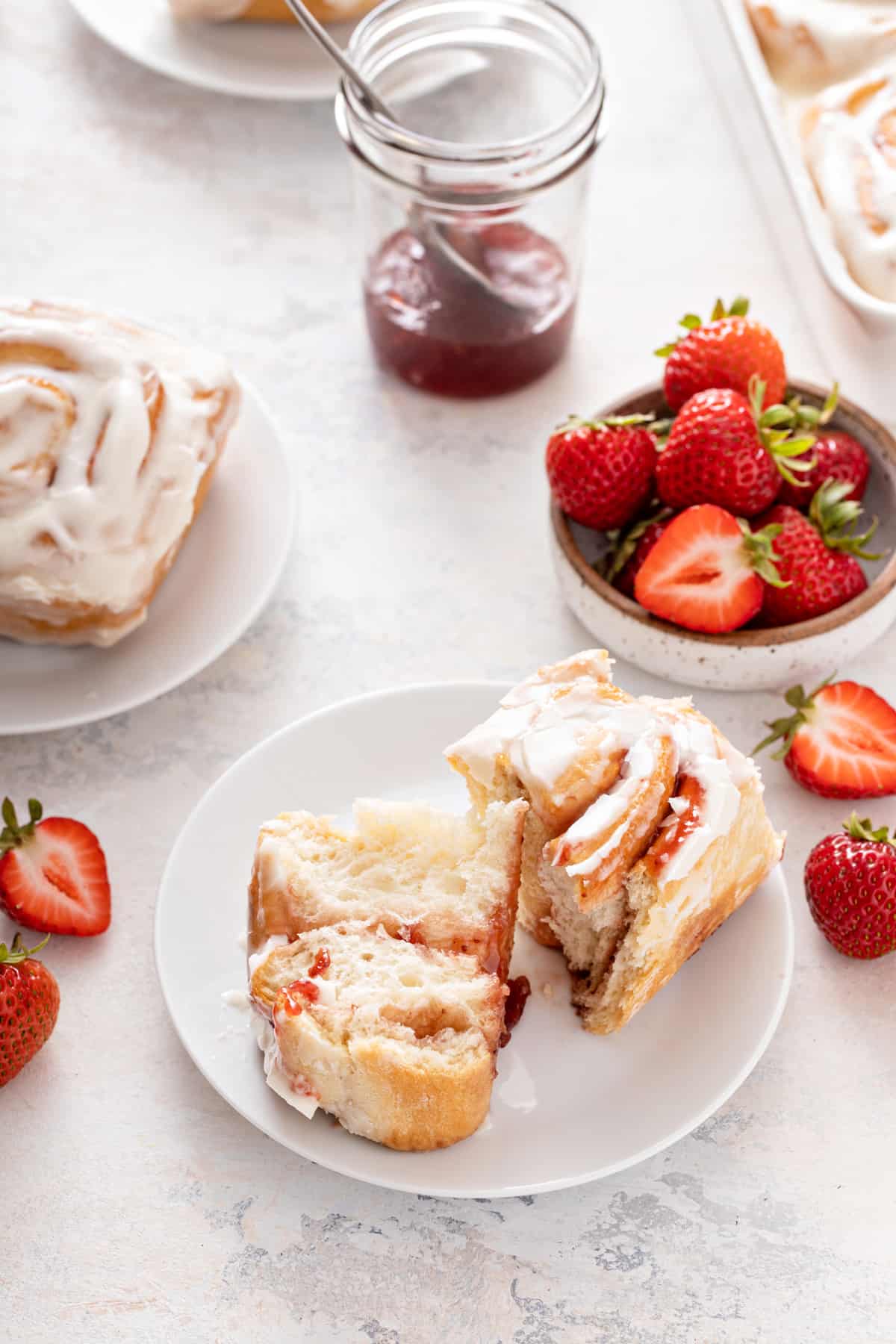 White plate with a halved strawberry sweet roll set on it.