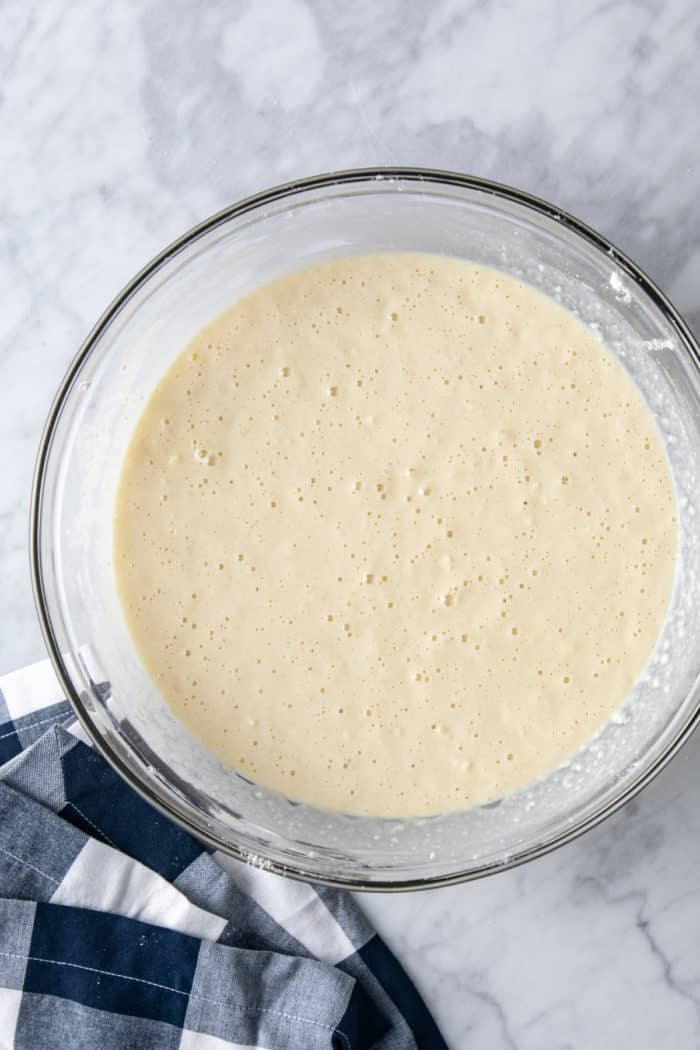 Easy coffee cake batter in a glass mixing bowl, set on a marble counter.