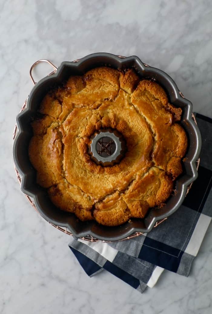 Baked easy coffee cake in a bundt pan, cooling on a kitchen towel.