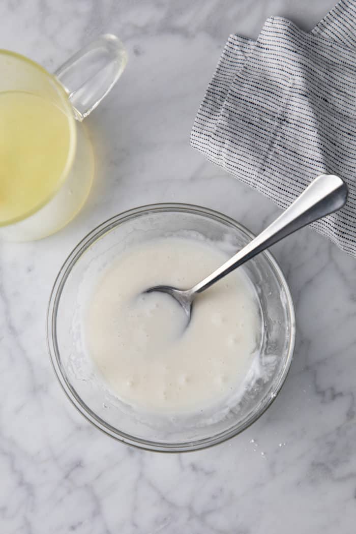 Lemon glaze being stirred together in a glass bowl.