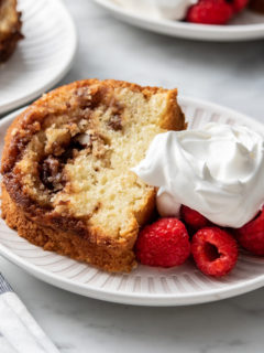 Plated slice of easy coffee cake next to fresh berries and whipped cream.