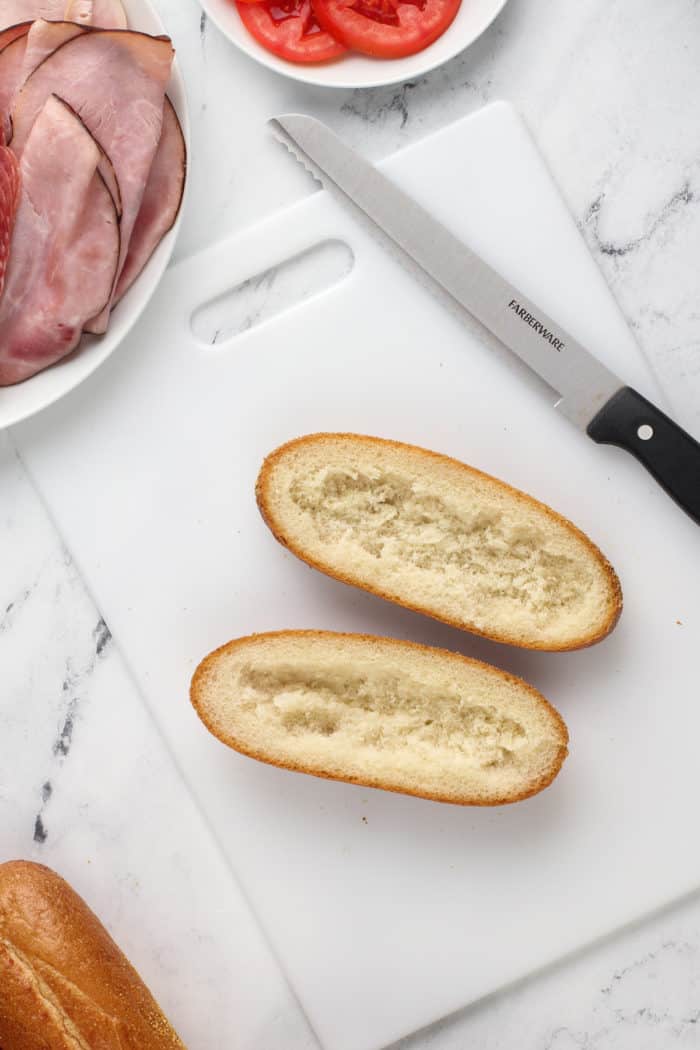 Grinder sandwich roll cut in half with the insides of the bread scooped out.