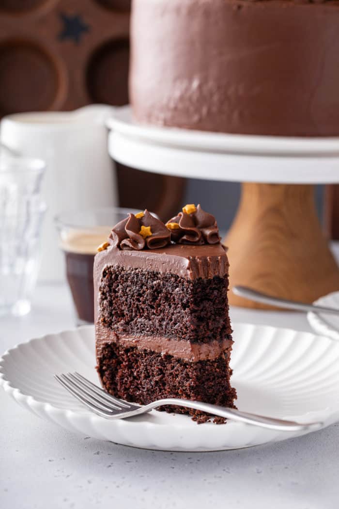 Slice of black magic cake with a bite missing, set on a white plate next to a fork.