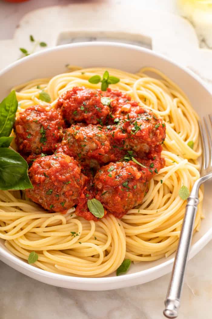 Meatball meat mixture in a metal mixing bowl set on a marble countertop.