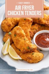 Close up of air fryer chicken tenders on a platter next to honey mustard sauce, barbecue sauce, and slices of lemon. Text overlay includes recipe name.