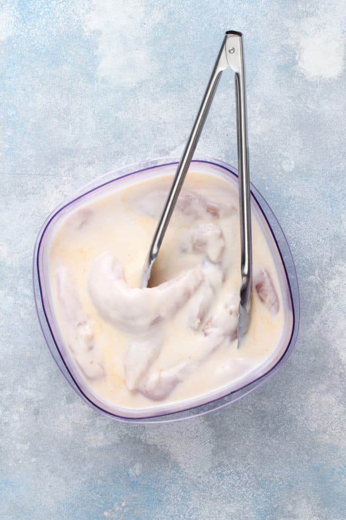 Chicken tenders soaking in a buttermilk brine.