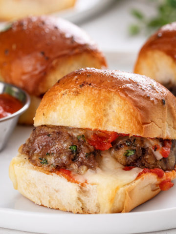 Close up of meatball slider on a white plate.