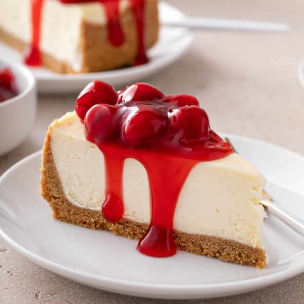 Slice of cherry cheesecake on a white plate.