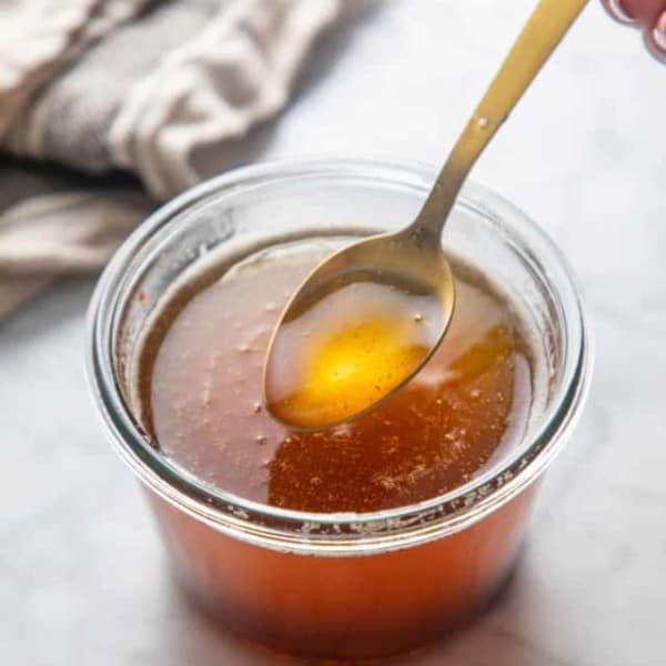 Spoon picking up a bit of brown butter from a jar of brown butter.