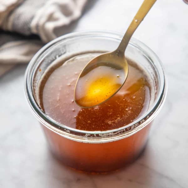 Spoon holding up a bit of brown butter over a jar of brown butter.