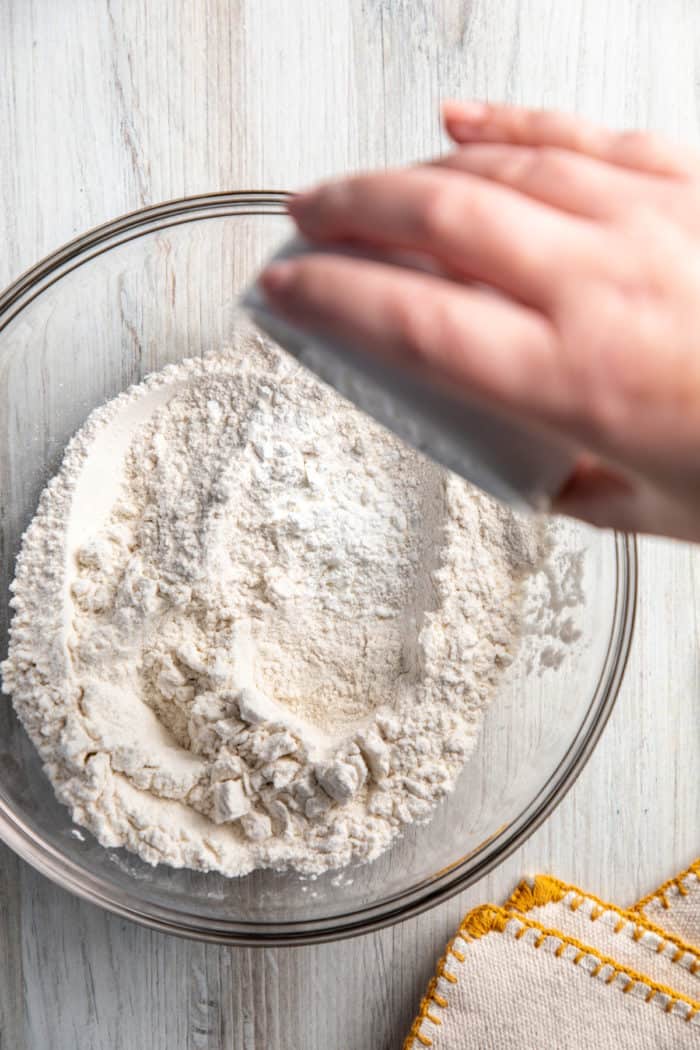 Cornstarch being added to a bowl of all-purpose flour.