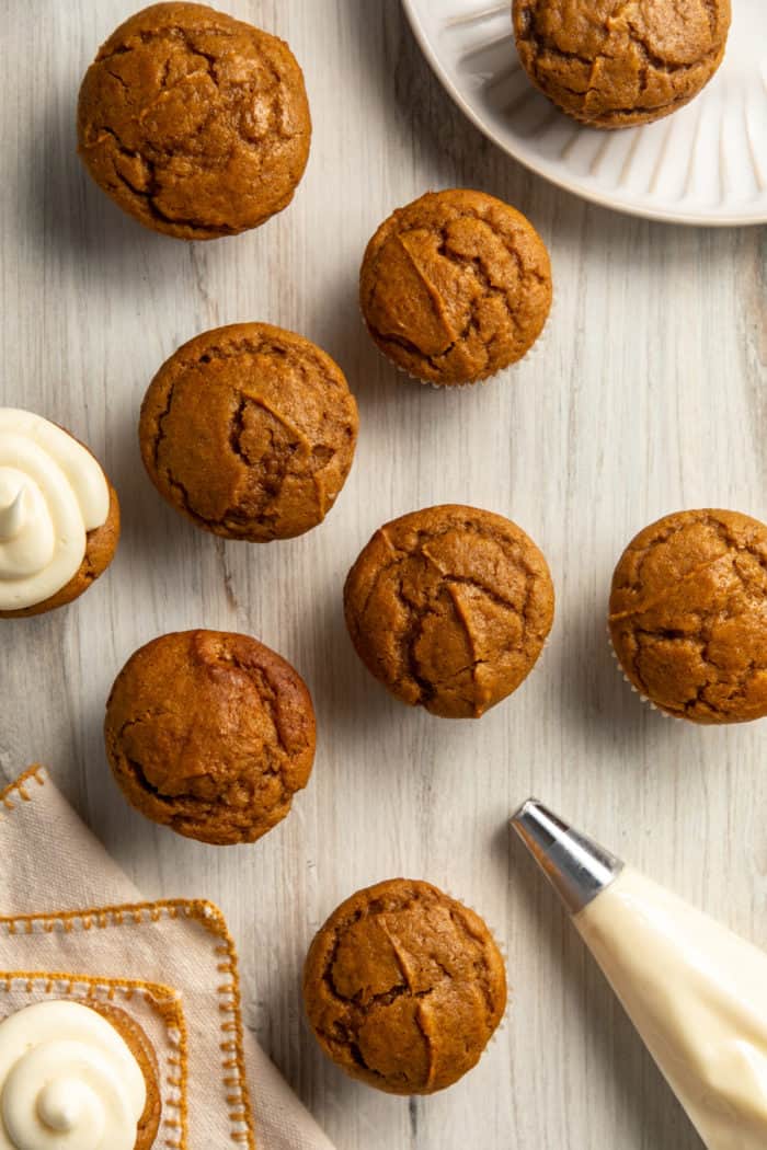 Cupcakes and a piping bag of frosting on a wooden countertop.