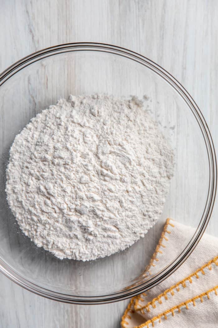 Cake flour substitute in a glass mixing bowl next to a tea towel.