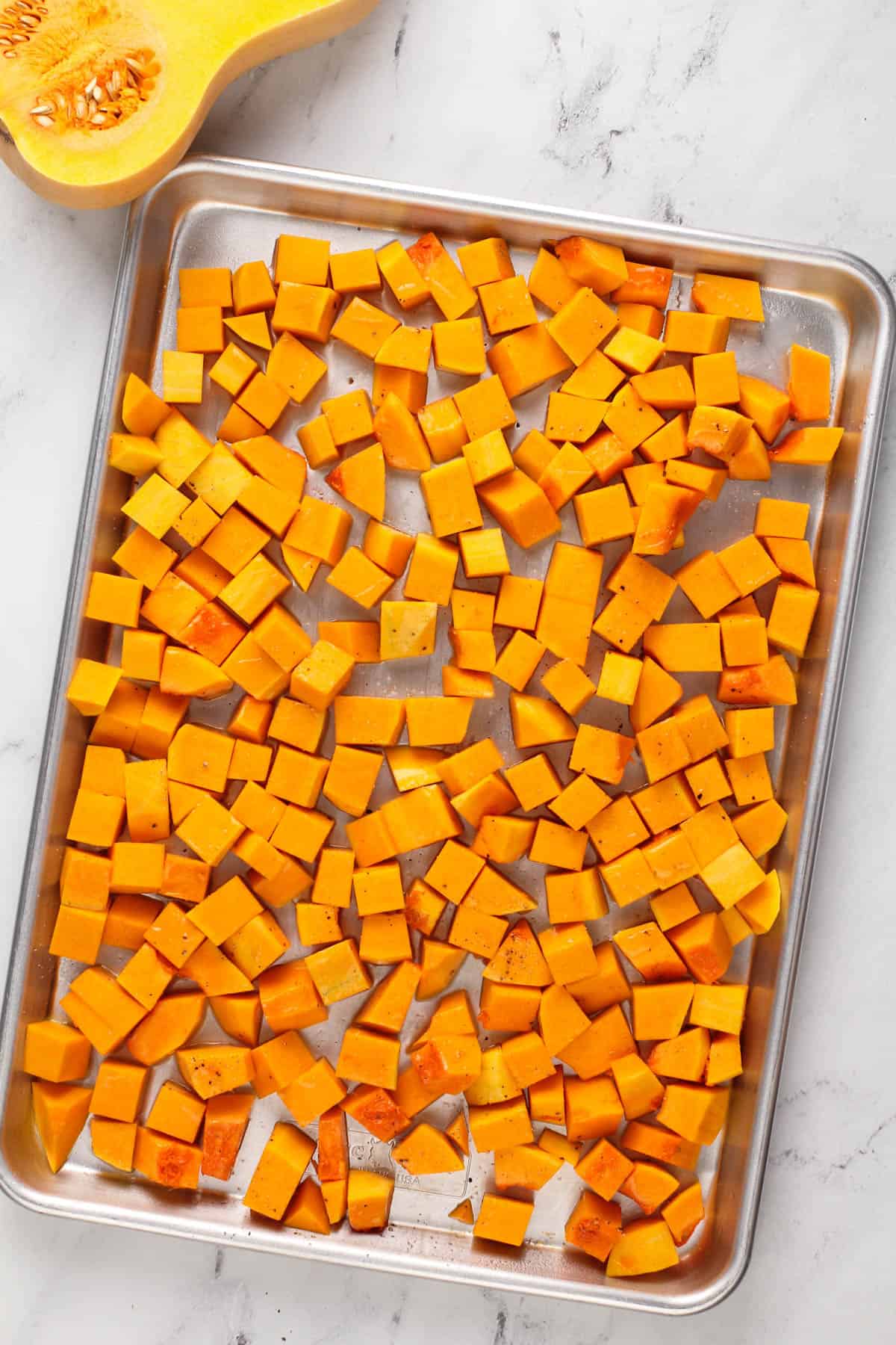 fresh butternut squash diced on a silver sheet pan