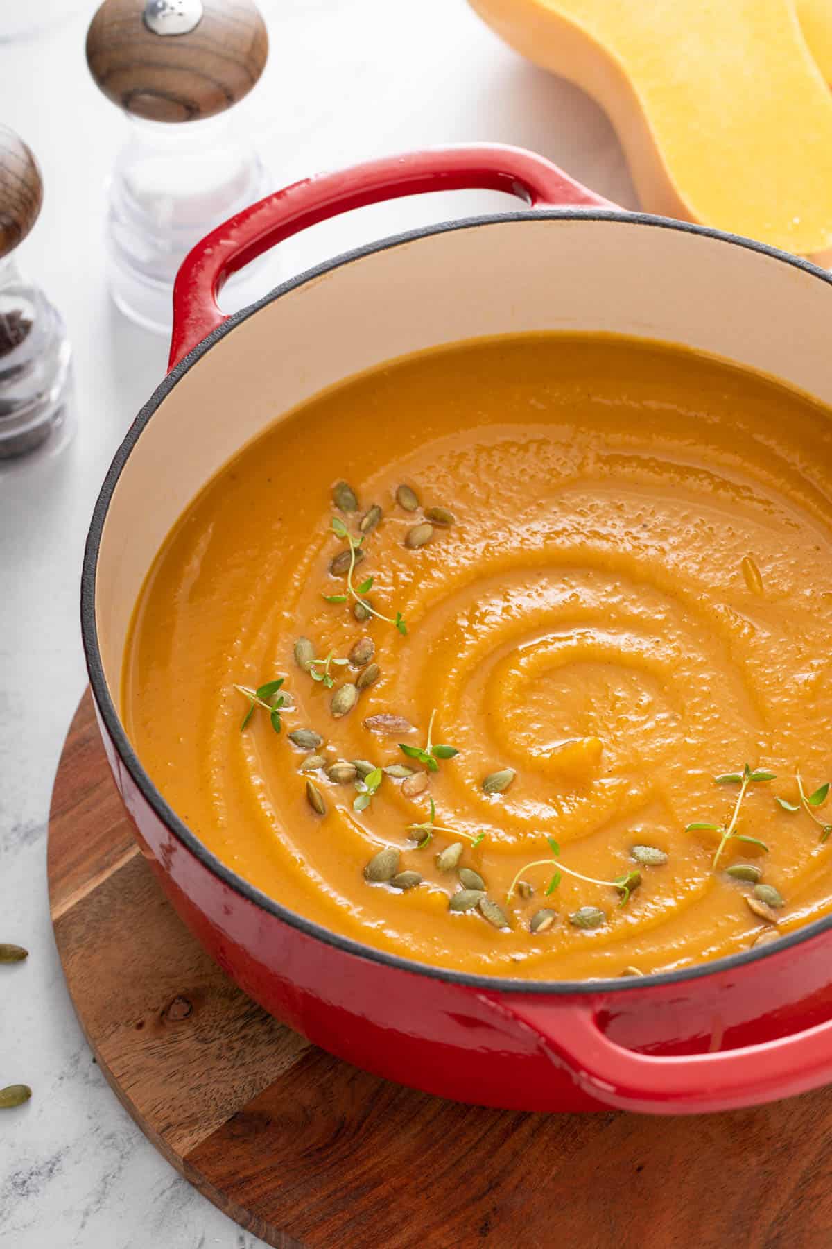 a pot of butternut squash soup resting on a wood trivet