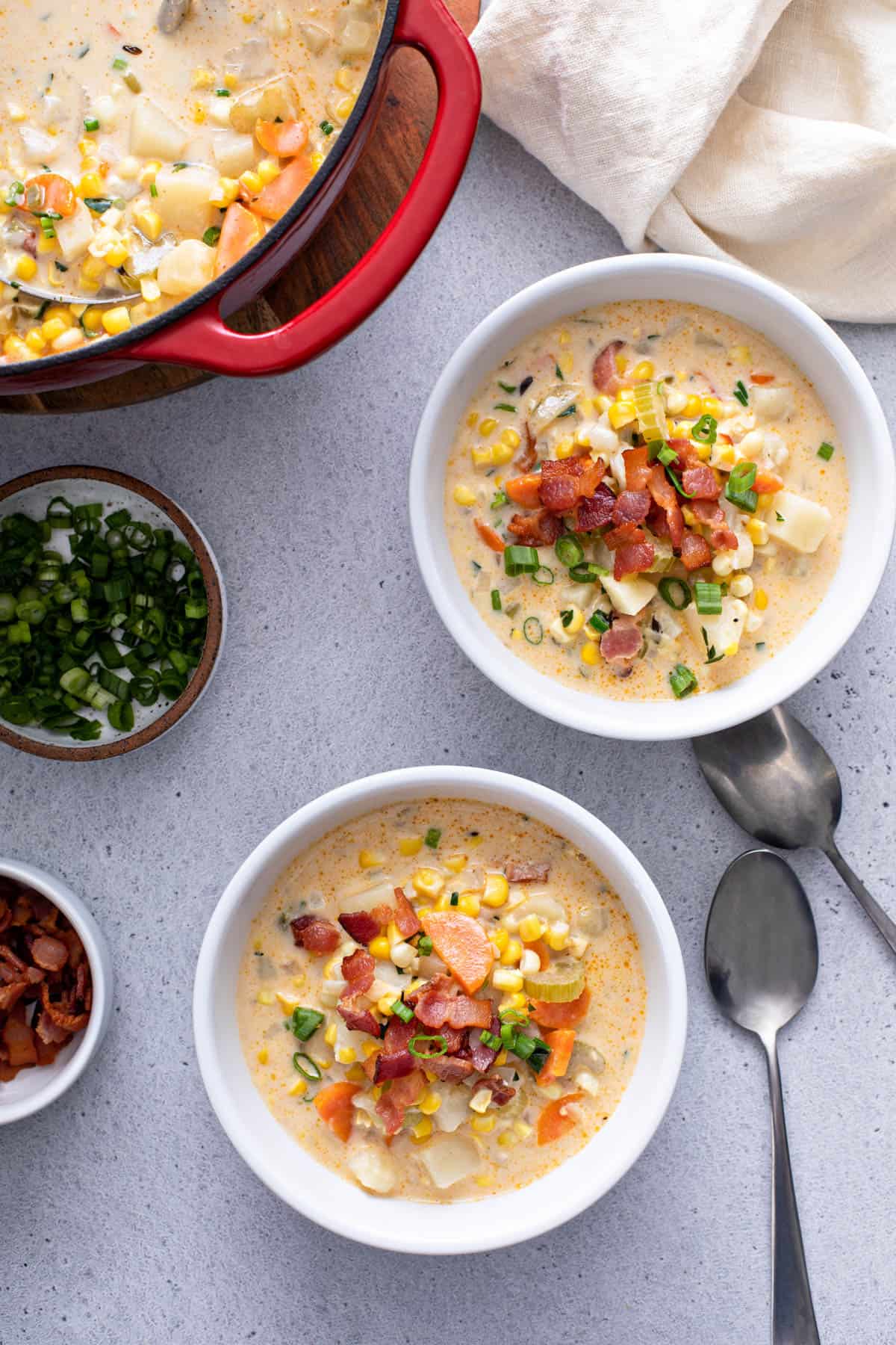 a pot of corn chowder next to two servings of the soup