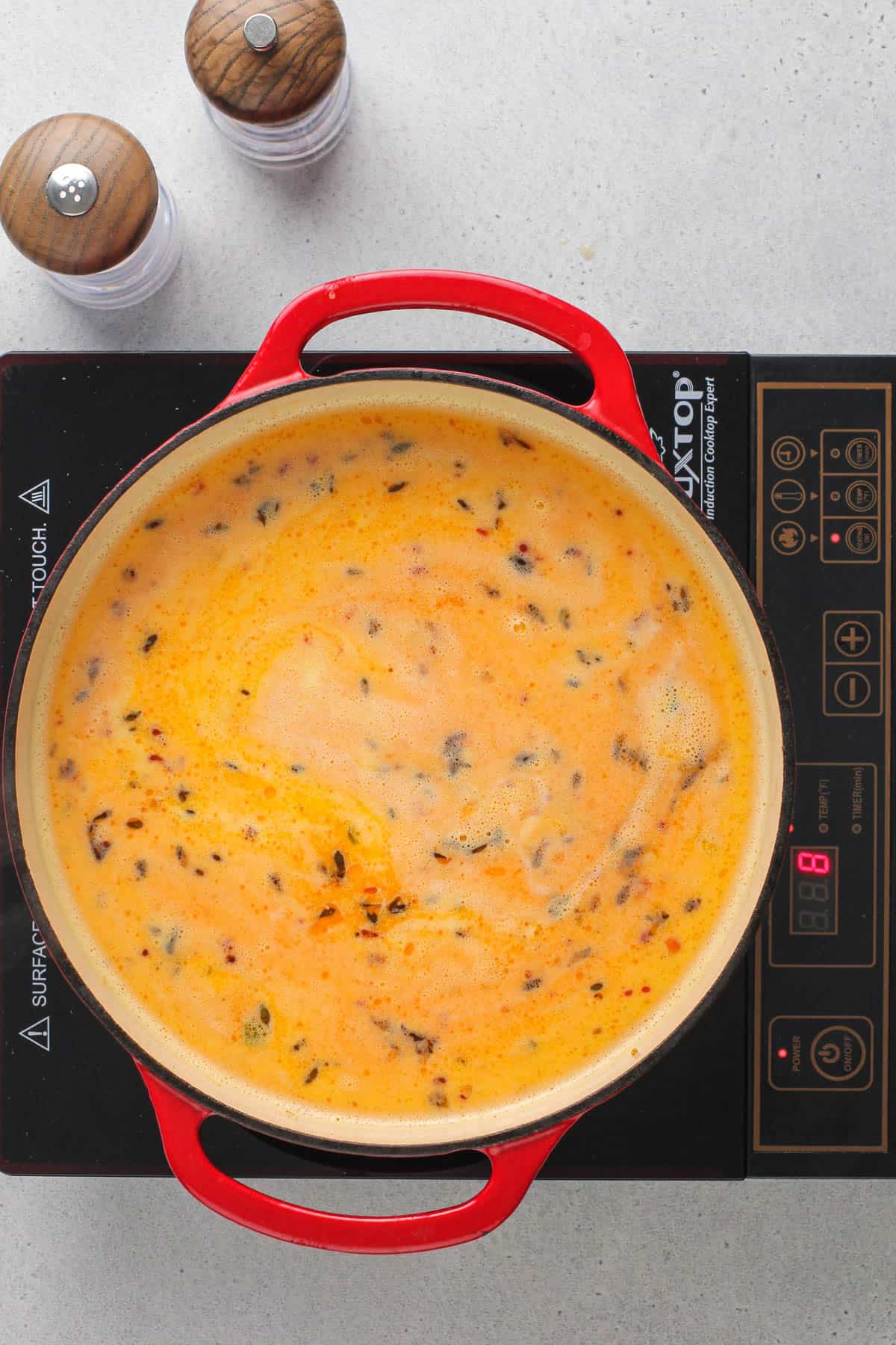 a red pot containing corn chowder cooking on the stove