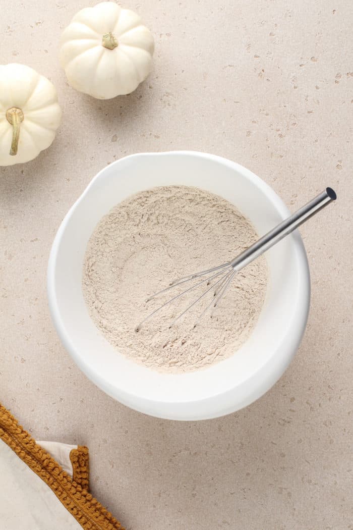 Dry ingredients for brown butter pumpkin bread being whisked together in a white mixing bowl.